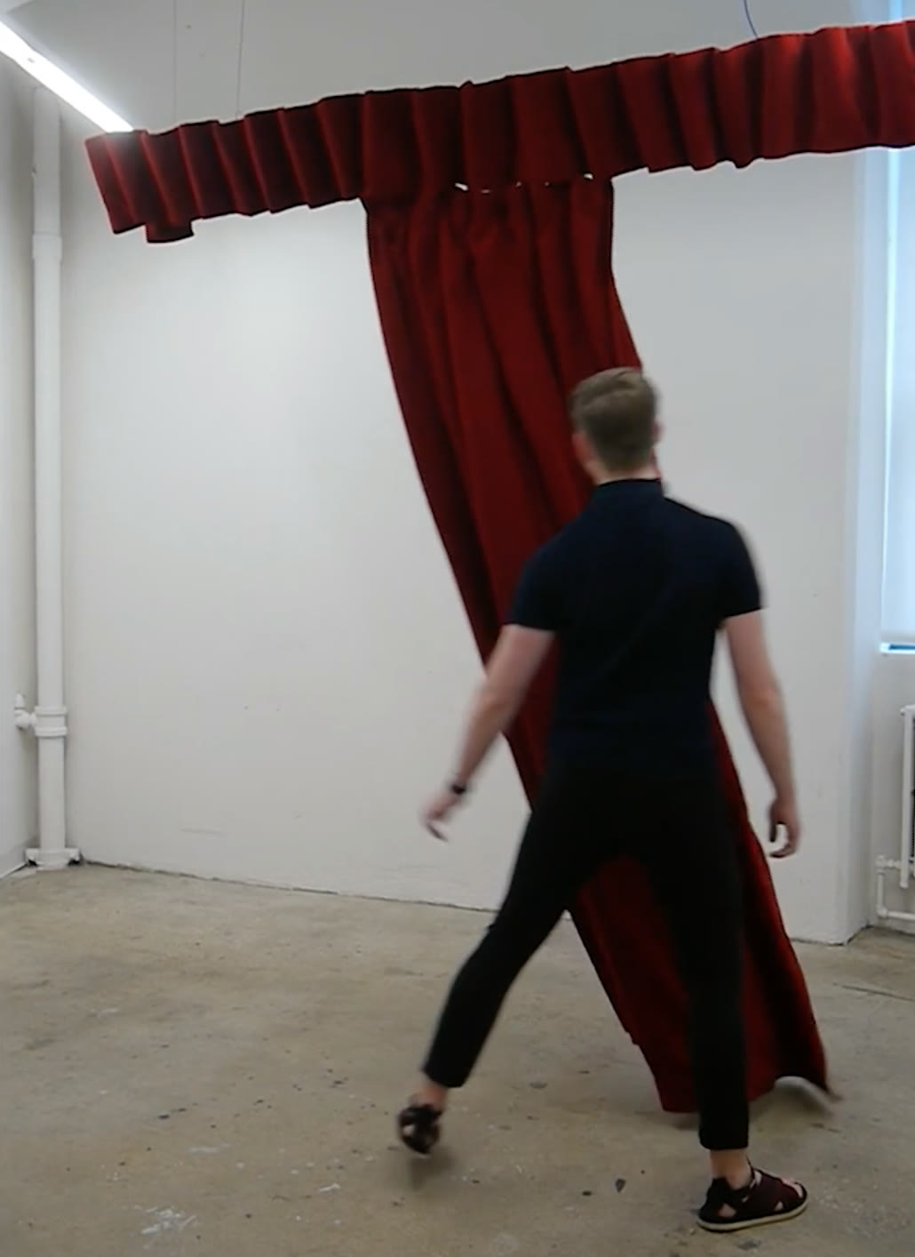 The curtain sliding along its track to stay in front of the moving visitor