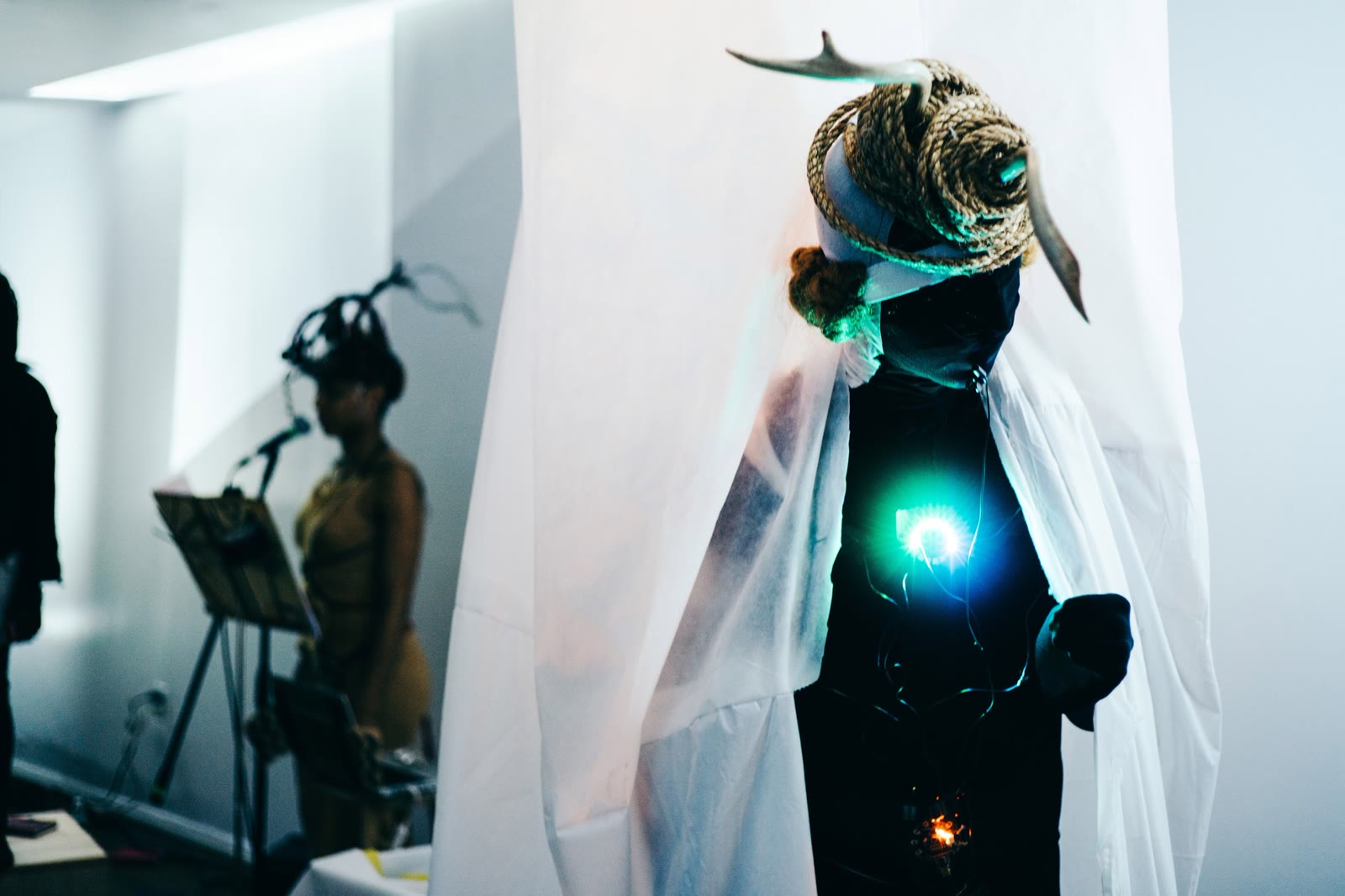 A costumed performer in a white cape with a glowing blue light at the chest